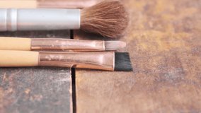 Close up footage of various used make up brushes on wooden board. Tracking shot. Selective focus.