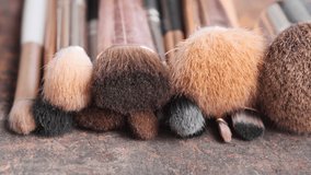 Close up footage of various used make up brushes on wooden board. Panning to the right. Selective focus.