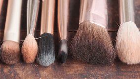 Close up footage of various used make up brushes on wooden board. Panning to the left. Selective focus.