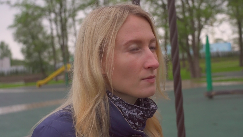 Young beautiful blond woman eating crackers or chips in the park. outdoors. chews and enjoys the taste.