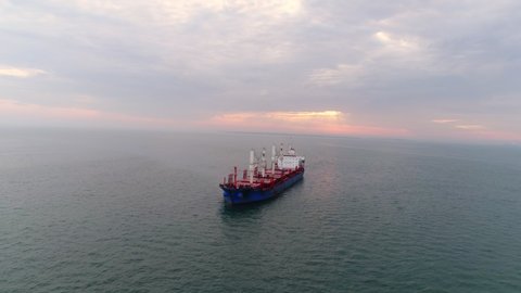 Aerial view anchoring cargo ship in harbour of Lisbon. Drone flying above water showing seascape in cloudy day, motionless footage opposite lonely tanker floating in ocean