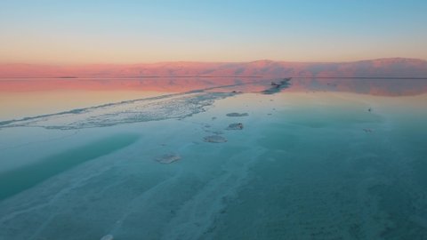AERIAL, incredible view on the dead sea of an aqua color with beautiful red mountains in the background and a beautiful blue sky