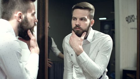 Close up of man looking in the mirror and checking out his new beard style