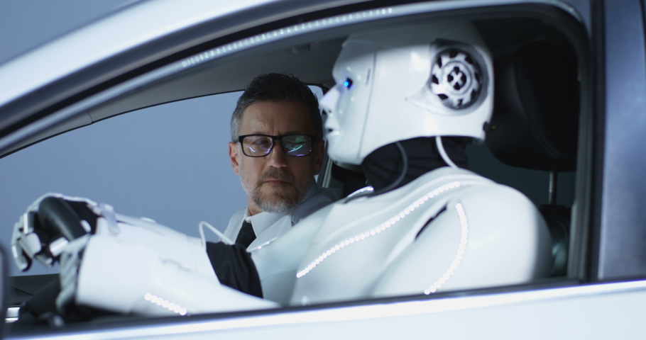 Medium close-up of two male scientists testing a car driving humanoid robot