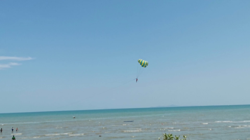 parasailing activity. colorful parasailing wing flying with tourist in the blue cloudy sky, extreme sport, summer activities at the beach
