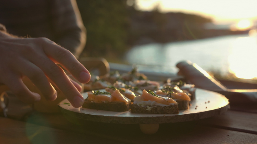 Salmon and cream cheese on bread. Picnic food by the beach. Beautiful sunset light Royalty-Free Stock Footage #1029889190