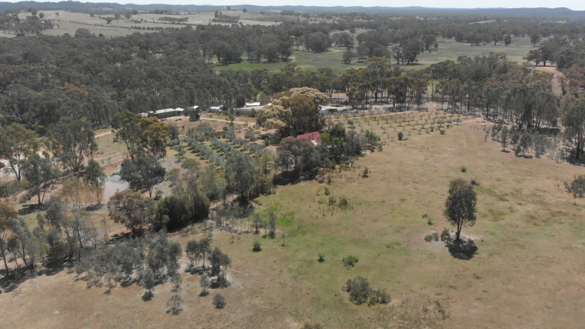 Aerial over panning down on to barn structure in farming environment.