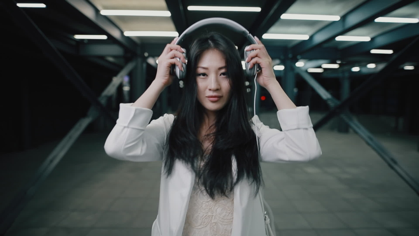 Asian woman puts on headphone walking at night underground | Shutterstock HD Video #1029905129