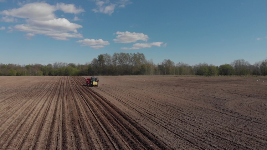 Tractor plowing fields, preparing land for sowing. Aerial view. Farmer in tractor preparing land in farmlands. Tractor plows a field. Agriculture industry, cultivation of land