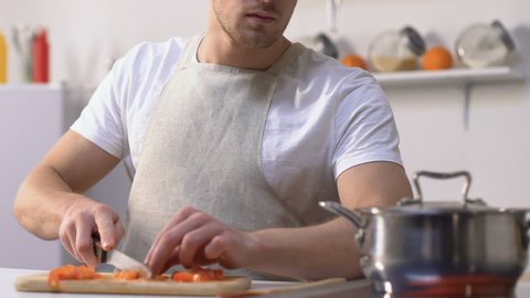 Man trying sauce in pan and screwing up face because of bad taste, cooking