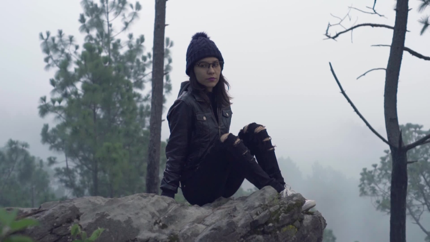 Girl posing in the rock on wild foggy environment