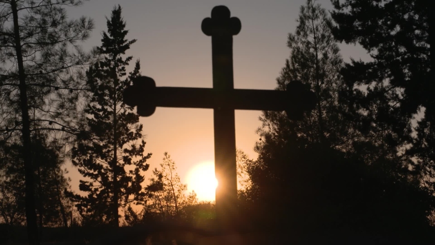 Silhouette of a cross on a hill at sunset
