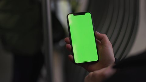 NEW YORK - 5 April 2018: Girl hands use touch holding a mobile telephone with a vertical green screen in tram chroma key smartphone woman close up technology cell phone street touch slow motion