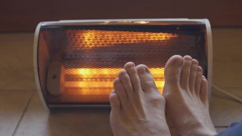 Feet move joyfully next to a home heater / radiator in apartment