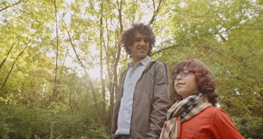 South asian family of four walking in autumn park, happily smiling and looking at each other - young family concept 4k