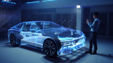 Automotive Engineer Working on Electric Car Chassis Platform, Using Tablet Computer with Augmented Reality 3D Software. Innovative Facility: Vehicle Frame with Wheels Becomes a Solid Virtual Model.