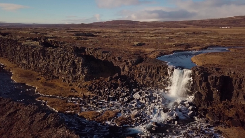 A CIRCLING AERIAL VIEW of a beautiful waterfall and river through a canyon.