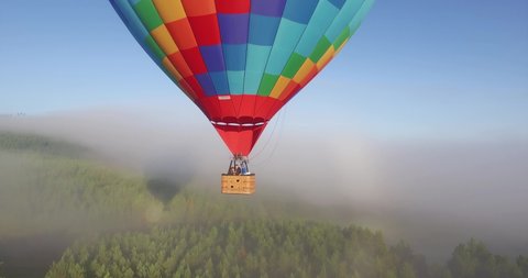 Colorful hot air balloon epic flying above mountain over the fog at sunrise with beautiful sky background - Aerial drone view