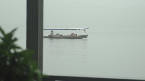 Hangzhou, China - April 27 2019: a single boat drifts on a lake in heavy fog with foreground motion