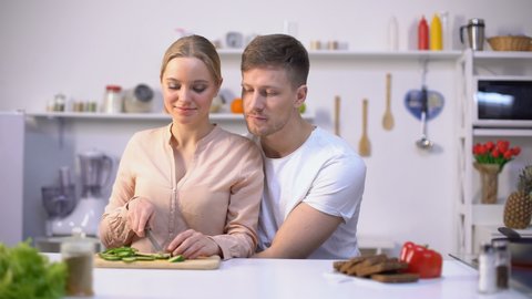 Romantic couple cooking salad, lovingly embracing, happy healthy vegan lifestyle