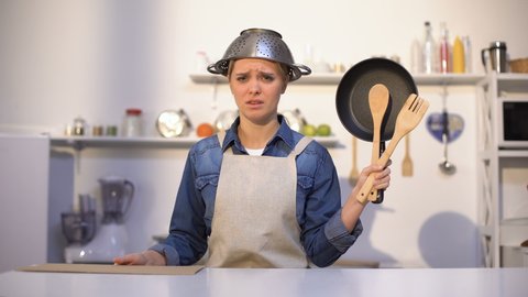 Inexperienced housewife asking for help in cooking, wearing pot on head, joke