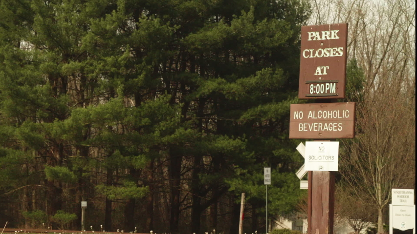 Wooden Park Closes Sign on Post by Road PAN RIGHT SLOW MOTION