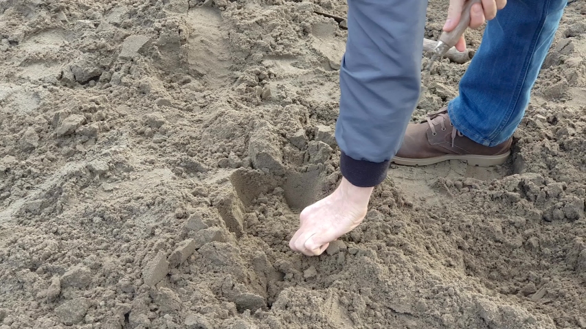 Man Scooping Sand lookin for some in it.