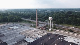 Industrial building in Michigan. Aerial drone footage flying by the building and adjacent train tracks. Water tower and smoke stack visible.
