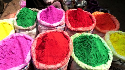 zoom in on vividly colored bags of holi powder at the spice market of chandni chowk in old delhi, india
