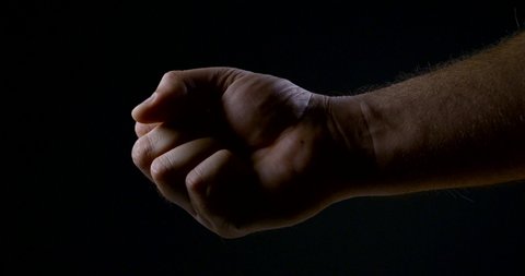 a man squeezes his hand in the dark. strong male grip