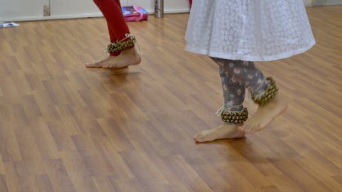 Two Indian girls wearing ghungroo and practicing Kathak dance in the music academy.
