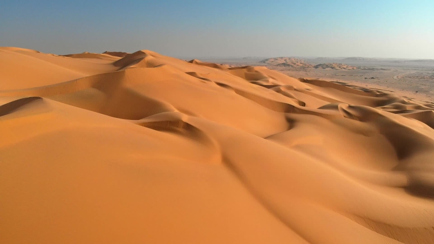 Aerial shot of sand dunes in desert. Flying over endless yellow sand dunes at sunset Royalty-Free Stock Footage #1029967640
