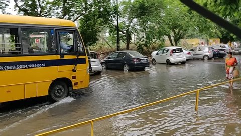Gurgaon, Haryana, India 05/22/2019 - School bus with children crossing sewage water. Untreated sewage being discharged from a sanitary sewer. Spilling on the roads in residential area.