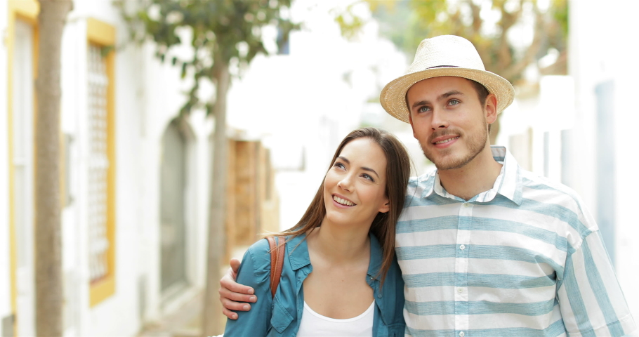 Happy couple of tourists walking contemplating views in a town street