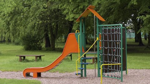 Empty playground after rain. Slide got wet in raindrops. Summer or spring rainy day. No people. No children.
