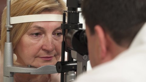A close-up shot of a senior female patients face during vision examination by using slit lamp. Vision testing for senior people.