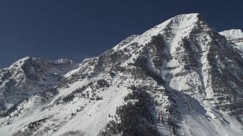 Aerial panning shot of snow covered mountain range / Aspen Grove, Utah, United States
