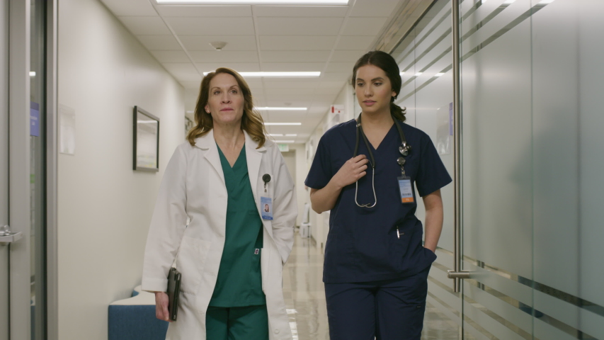 Slow motion of doctor and nurse walking and talking in hospital corridor / Salt Lake City, Utah, United States