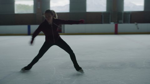 Slow motion of woman practicing figure skating on ice skating rink / Murray, Utah, United States