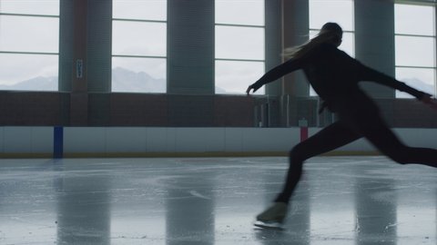 Slow motion of woman practicing figure skating on ice skating rink / Murray, Utah, United States
