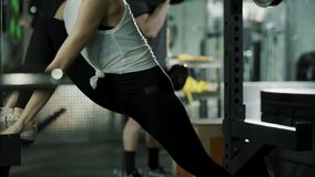 Man lifting barbells staring at woman stretching leg in gymnasium / American Fork, Utah, United States