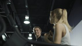 Tilt up to man flirting with woman while running on treadmills in gymnasium / American Fork, Utah, United States