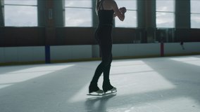 Slow motion low angle view of woman practicing figure skating on ice skating rink / Murray, Utah, United States