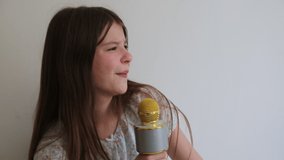 Teen girl is listening to music and singing with microphone