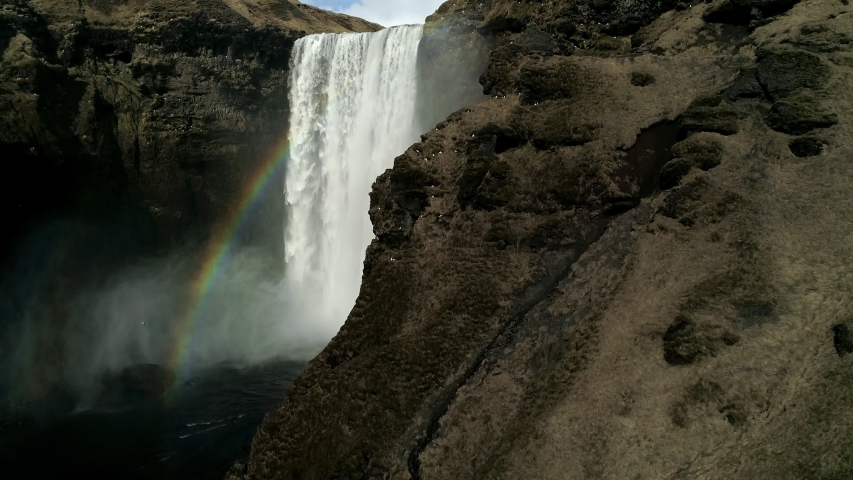 Flying near Skogafoss Waterfall in the South of Iceland. Aerial shot of high water cascades and a colorful rainbow apperance. Royalty-Free Stock Footage #1030014875