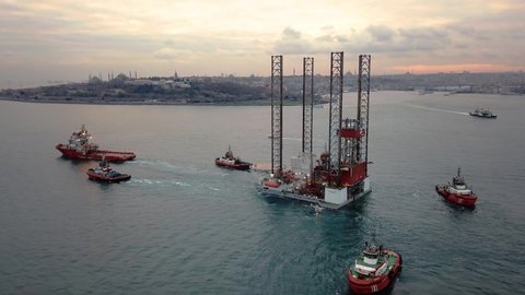 ISTANBUL - CIRCA 2018: Flying over. Convoy of the GSP Saturn offshore drilling rig in front of Sarayburnu, Old Istanbul. Offshore boat or tugboats towing the oil platform barge on sunset
