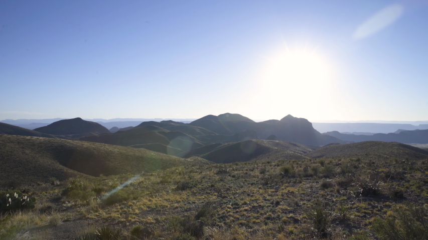 Dolly right shot of dry highlands, and mountain peaks against the sun, with copy space
