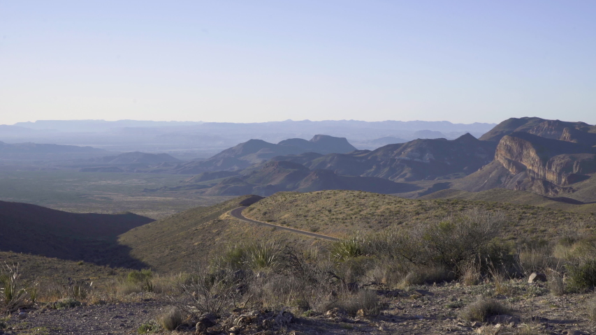 Dolly left wide shot of mountain scenery, asphalt road on the side of a hill in the distance