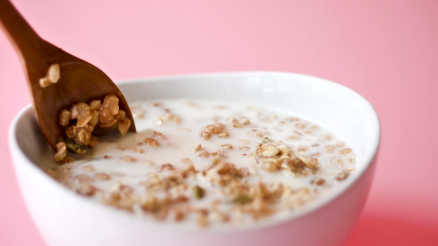 Hand scoop whole grain corn flake from white bowl, pink background and slow motion. | Shutterstock HD Video #1030023017