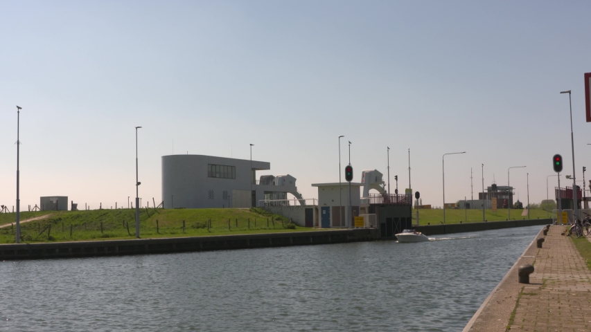 small cruiser departs the lock of the weir complex Amerongen, which regulates 
the water level in the river Rhine. In background the new Control Center. AMERONGEN, THE NETHERLANDS - APRIL 2019